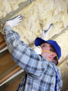 Worker thermally insulating a house attic using mineral wool
